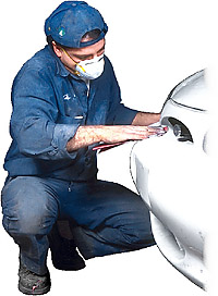 Vehicle body repairer working on car bumper
